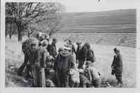 Group kneeling and standing looking at something in middle
