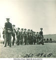Soldiers carrying rifles march in a line and look to their right, The University of Iowa, 1950s