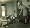 Woman tuning a large wooden radio for sitting children, The University of Iowa, January 12, 1938