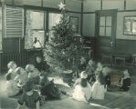 Children sitting around a Christmas tree in a classroom, The University of Iowa, 1920s