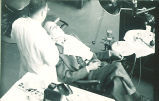Dental student looking at a patient's teeth, The University of Iowa, 1940s