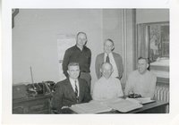 Two Men Standing and Three Men sitting in Office