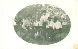 Men posing at table outside smoking pipes, Iowa, 1920s
