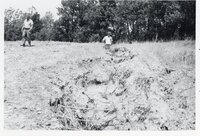 Two men look at eroded area in field