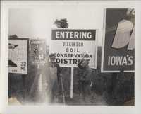 Bob Ingwersen and his Son Stand by the 'Entering' and 'Leaving Dickinson Soil & Water Conservation District' Sign.