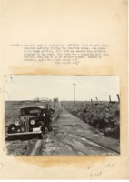 1937 - Man stands by car by roadside ditch filled with soil washed from hillside