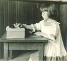 Girl plays with small knots of yarn, The University of Iowa, ca. 1920