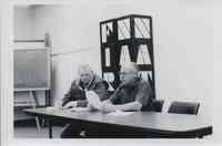 Two Men reading Document at Table