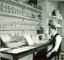 Man working with vials and chemistry equipment, The University of Iowa, 1930s