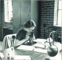 Student looking into microscope, The University of Iowa, 1930s