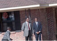 Two unidentified men and a boy stand by a brick building