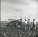 Four men observing a tractor with extra equipment performing work on the soil in a field, for a Rural Minister Short Course., 1961.