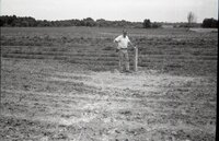Man stands next to pipe in field