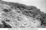 Man standing by oblique bedding in Sugar Creek lime quarries, Sugar Creek, Iowa, late 1890s or early 1900s