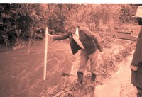 Man Measures Depth of Water in Flooded Area