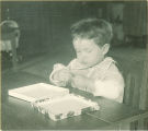 Small child playing with toys and a box, The University of Iowa, 1920s