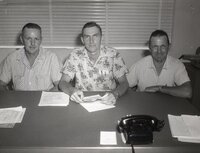 Three unidentified men sit in office at a desk
