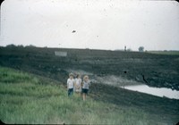 Three children stand in front of newly built structure.