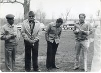 Men stand under tree during a meeting