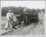 Three workers with McCormick-Deering harvester