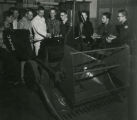 Students observing a large piece of agricultural equipment, 1957