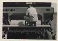 Man squats on Haybuster 107 seed drill