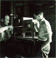 Men working in a laboratory with tongs and chemistry equipment, The University of Iowa, 1930s