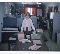 Woman Stands at Table Holding a Card in a Plastic Sleeve