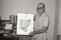 1975 Soil scientist Mel Brown man holds county oil survey map