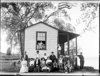 PA 134  Nineteen people at river cabin, flag