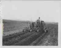 Tractor pulling disk in cornfield<br /><br />
