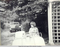 John, Jr. sitting in golf cart looking rt, near trellis and front entrance