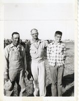 Three Men in Field Smile at Camera
