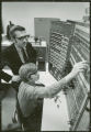 Two researchers work on a control panel, 1970
