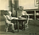 Small children sitting at a table reading, The University of Iowa, January 12, 1938