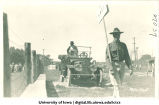 Military cadet with sign leading official in car for Senior Frolic, The University of Iowa, 1910s