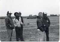 Five men stand near earthmover