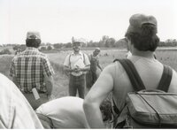 Man with hat, sunglasses, and beard in grassy field