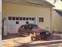 Car parked by gas pump and barn