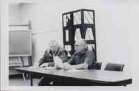 Two Men Reading Document at Table