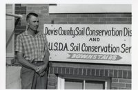 1964 - Sam Botts, Jr. stands beside Davis County Soil Conservation District sign