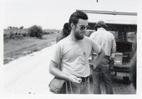 Three men stand in back of a van parked by a rural road
