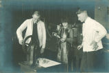 Pharmacy students using grinding machine in pharmacy laboratory, The University of Iowa, 1910s