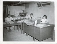 Three men and one woman work at office tables