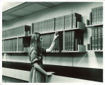 Woman with National Union Catalog volumes in Main Library, the University of Iowa, 1970s