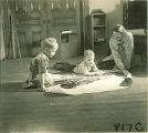 Woman showing children a poster about trains, The University of Iowa, January 12, 1938
