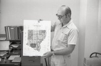 1975 Soil scientist Mel Brown man holds county oil survey map