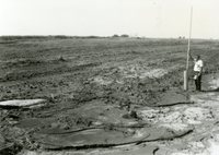 Man Stands by TOT Pipe in Field
