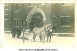 Horses pulling a snow plow in front of Armory, The University of Iowa, 1920s
