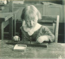 Toddler playing with a pegboard puzzle, The University of Iowa, 1920s